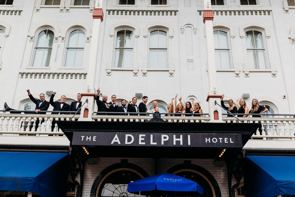 A wedding party cheering and celebrating on the covered outdoor terrace at The Adelphi Hotel